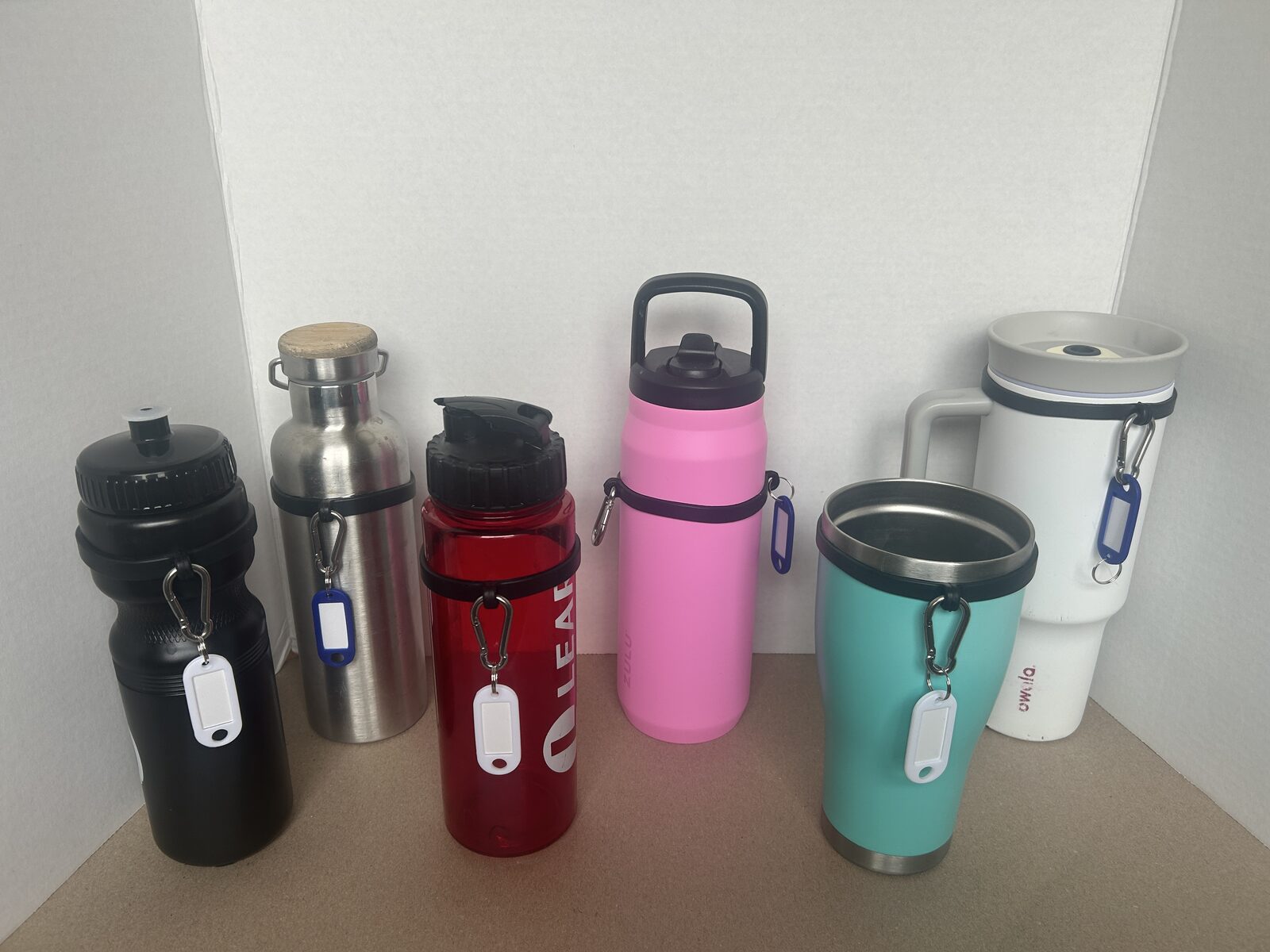 Silicone water bottle sling shown fitting six different bottle and tumbler styles